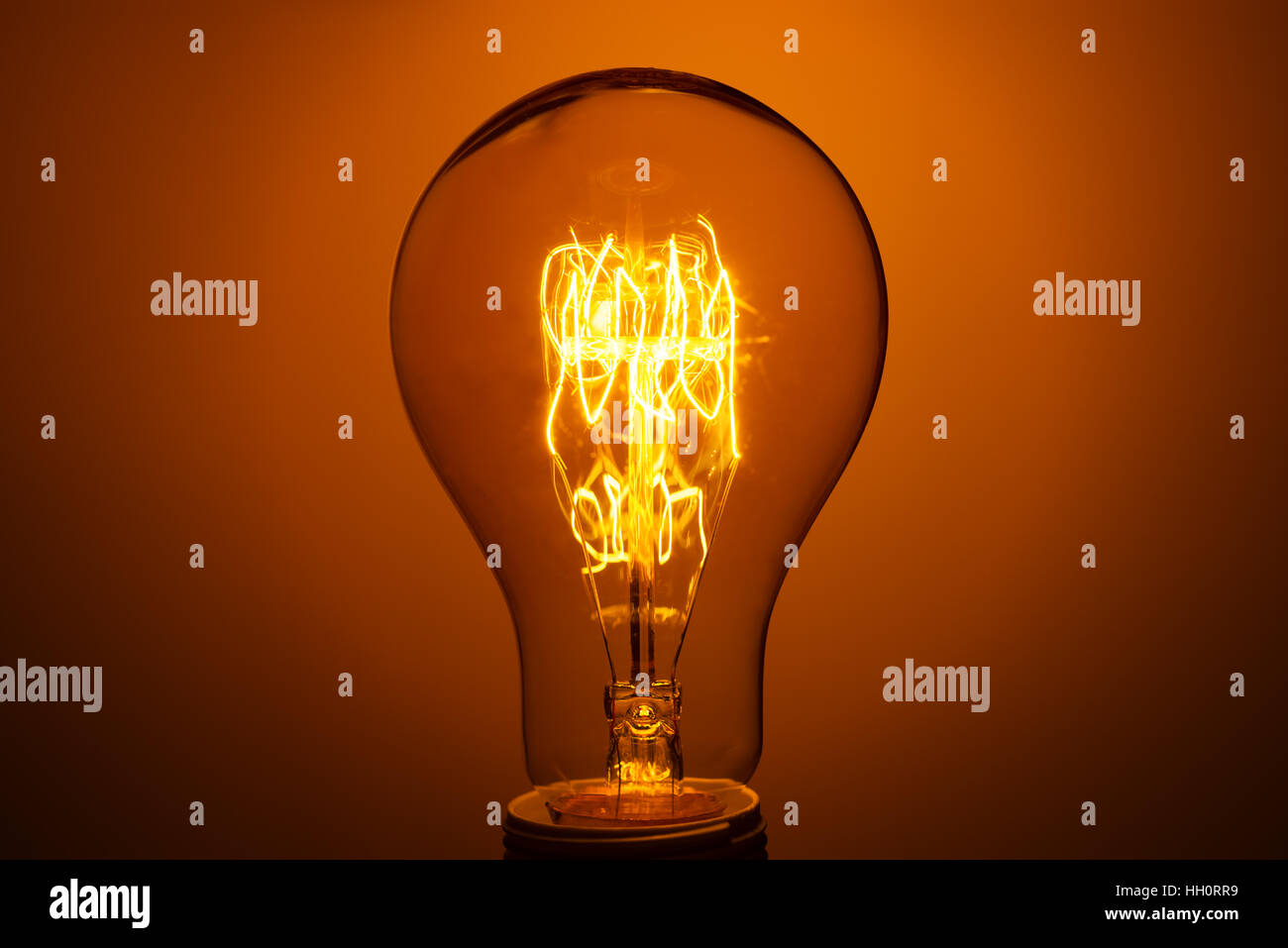 lighted vintage incandescent bulb on orange background Stock Photo