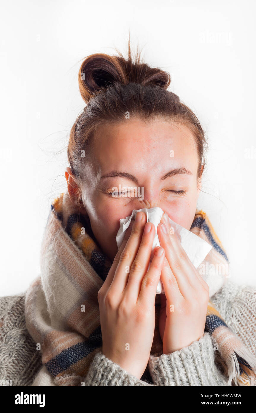 Girl with cold sneezing in handkerchief wearing scarf and sweater Stock Photo