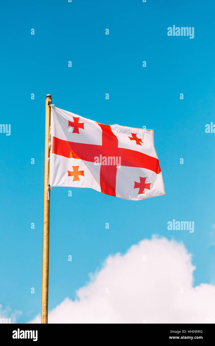 Close The Flag Of Georgia, Five Cross Flag, Waving On Flagpole At Blue Sunny Sky Background. The White And Red National Symbol, Civil And State Ensign Stock Photo