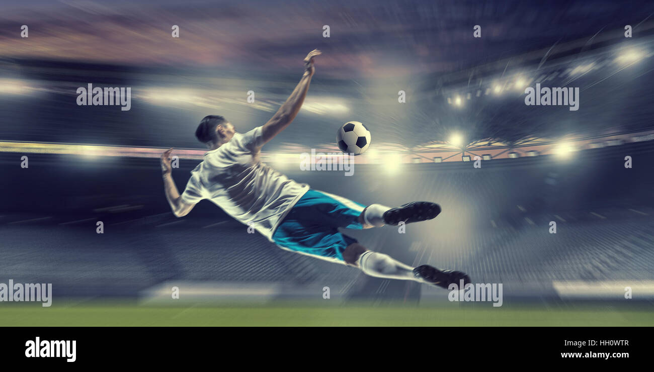 Football player at stadium hitting ball. Mixed media Stock Photo