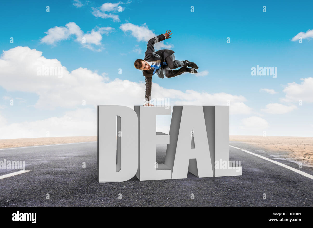 Young cheerful businessman doing handstand on word DEAL Stock Photo