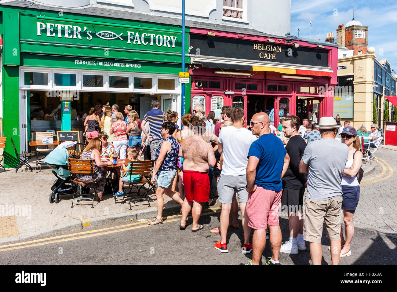 Long mid-day queue of people for fish and chip shop on seafront during heatwave at Ramsgate, UK. Summertime, bright sunshine. Stock Photo