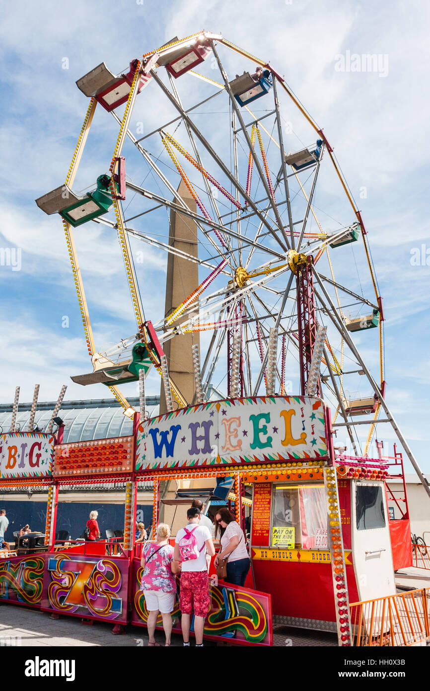 People buying tickets at booth for ferris wheel also known as big wheel ...