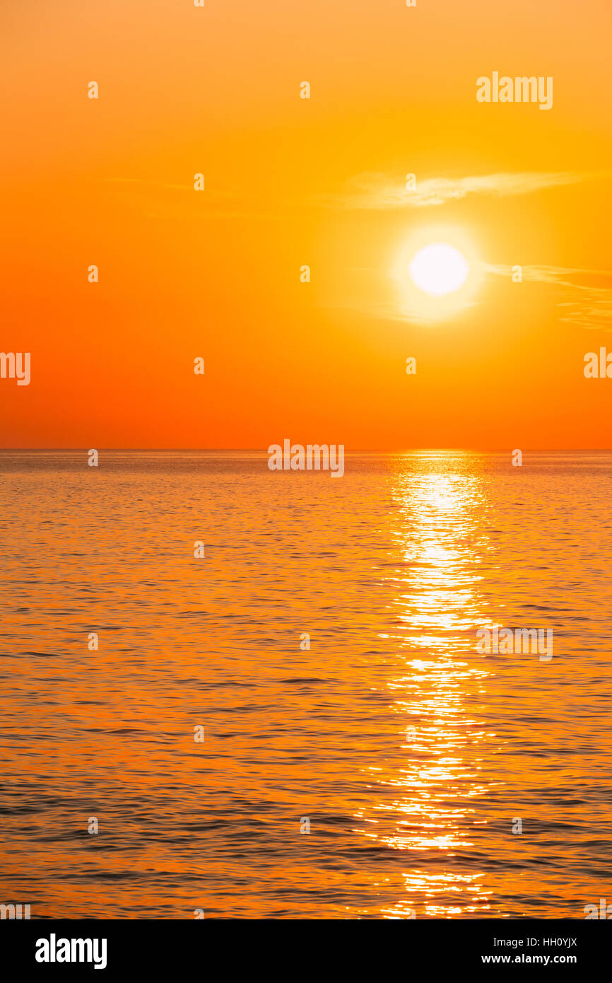 Sun Is Setting On Horizon At Sunset Sunrise Over Sea Or Ocean. Tranquil Sea Ocean Waves. Natural Sky Warm Colors. Stock Photo