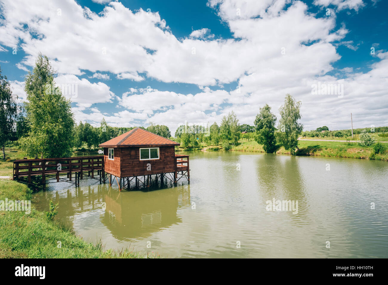 Wooden Pier For Fishing, Small House Shed And Beautiful Lake Or River In  Background. Picturesque Stock Photo by Great_bru