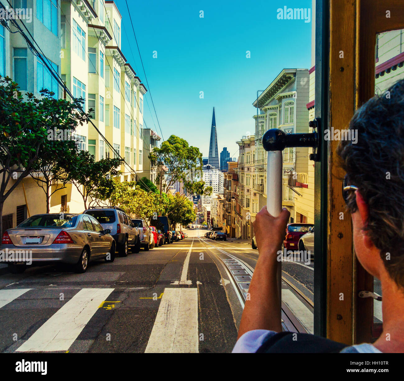 Ride with the cable car in San Francisco. Picture shows a person riding the famous MUNI train on Powell-Mason line down the hill to the bay with the f Stock Photo