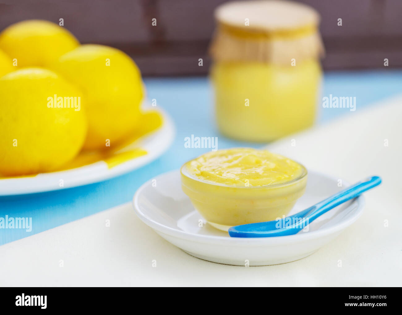 fresh organic homemade lemon curd showing lemons and lemon curd in a jar and glass dish, pretty with light blue and yellow colors, room for copy space Stock Photo
