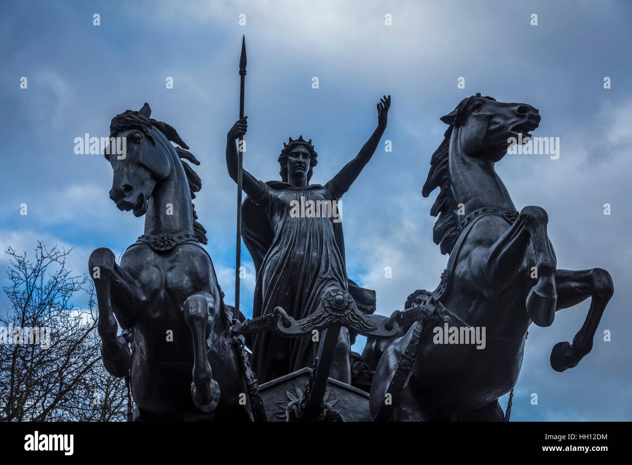 Image looking straight ahead and up of Queen Boadicea riding her chariot with two black horses and holding a spear Stock Photo