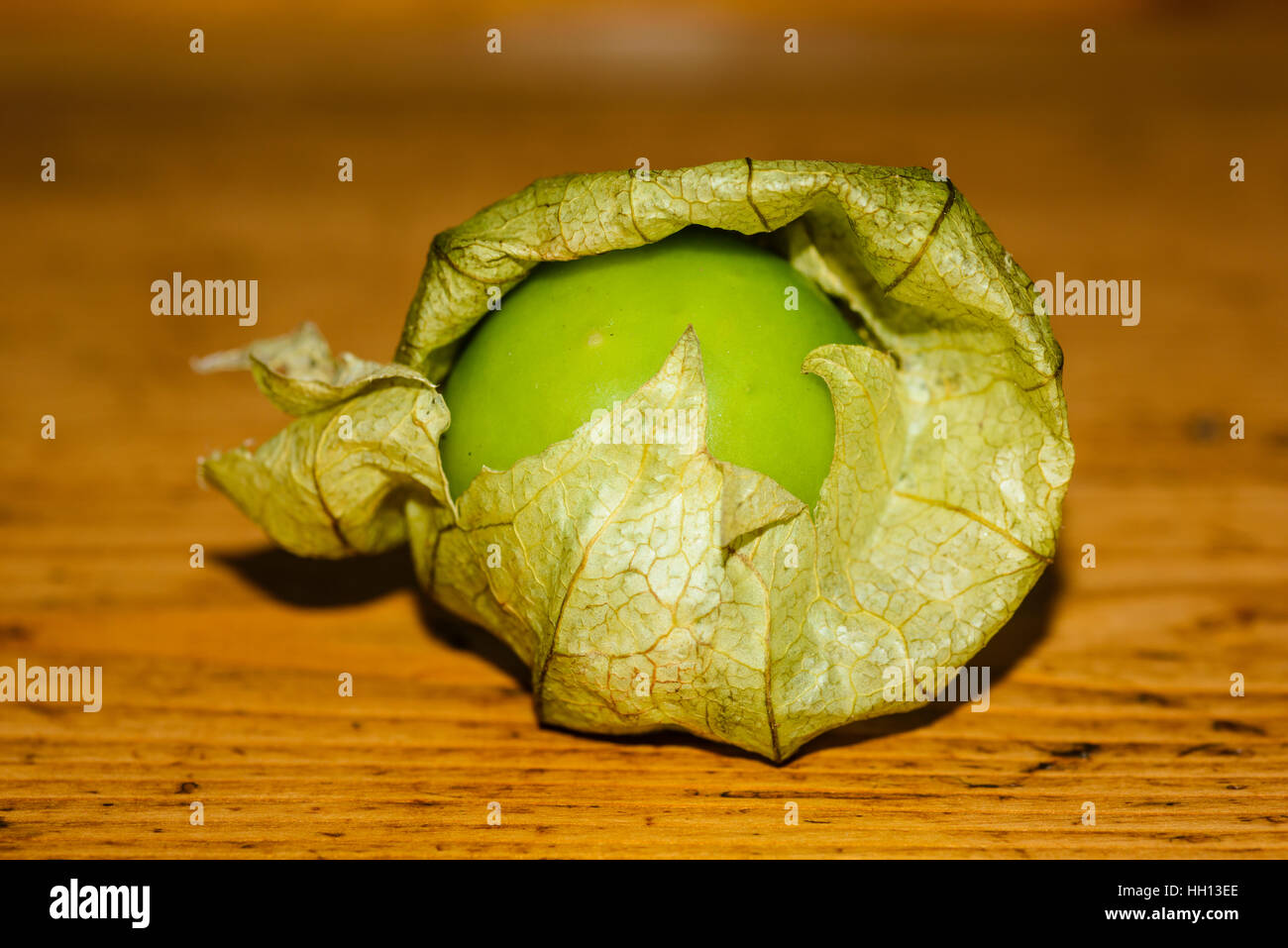 Closeup of tomatillo on well-worn wooden surface Stock Photo