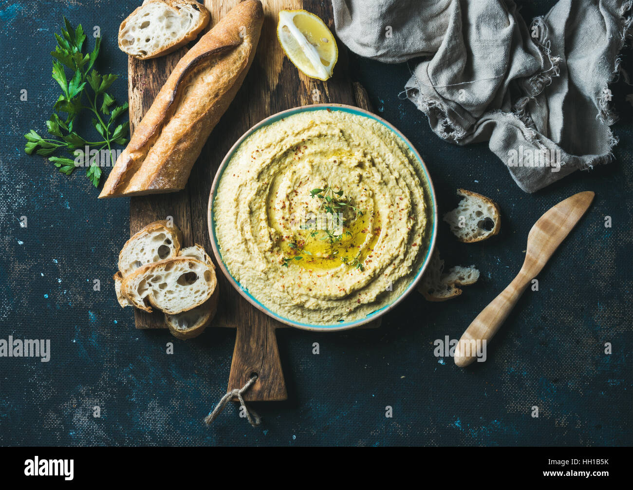 Homemade hummus with lemon, herbs and freshly baked baguette Stock Photo