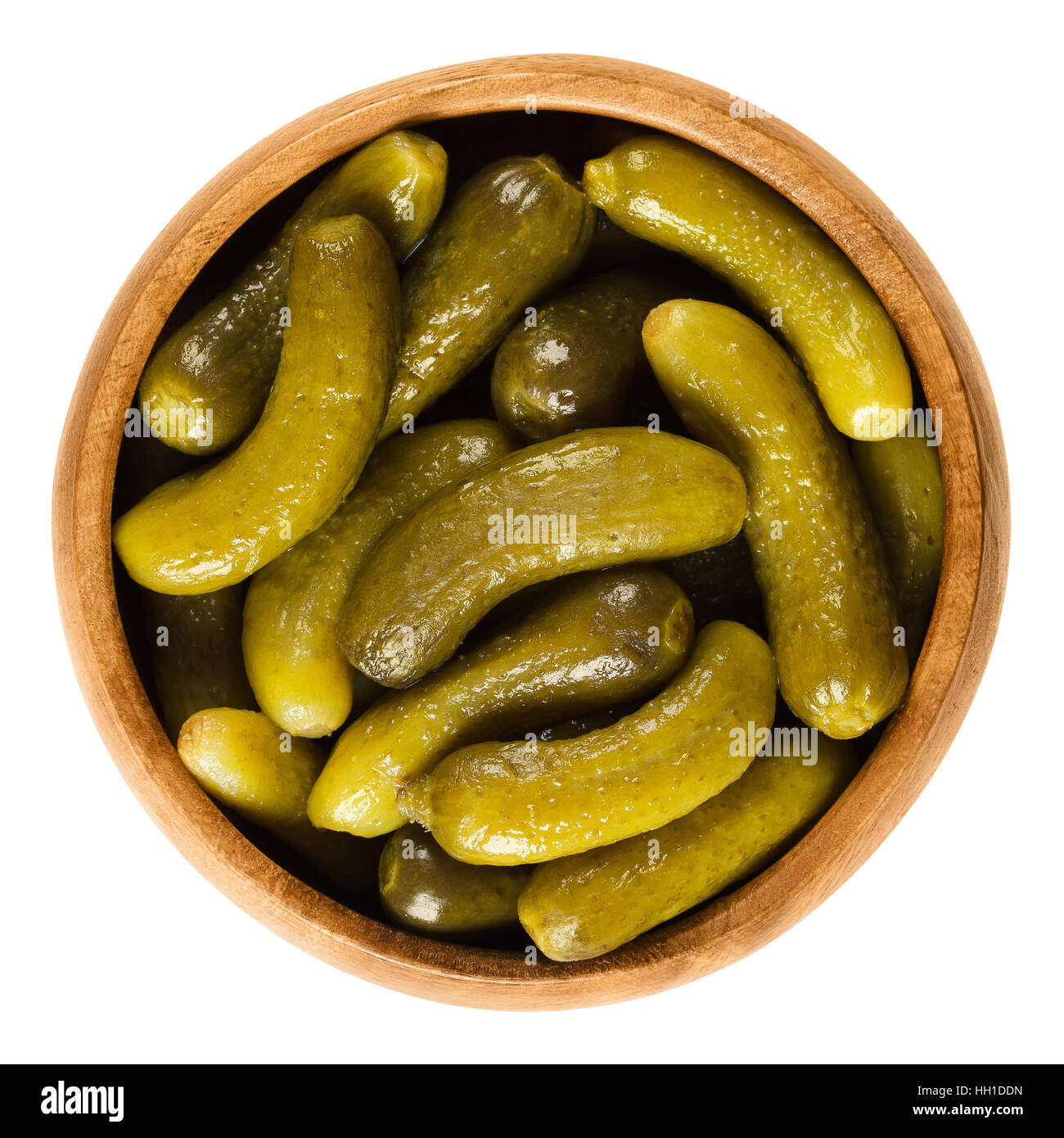 Cornichons, pickled cucumbers in wooden bowl. Green tart French pickles, made from small gherkins. Gherkin, known as pickle. Stock Photo