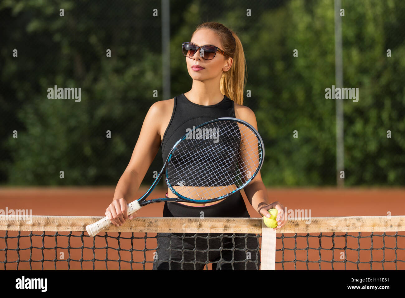Young woman at net with tennis racket, tennis court, Switzerland Stock Photo