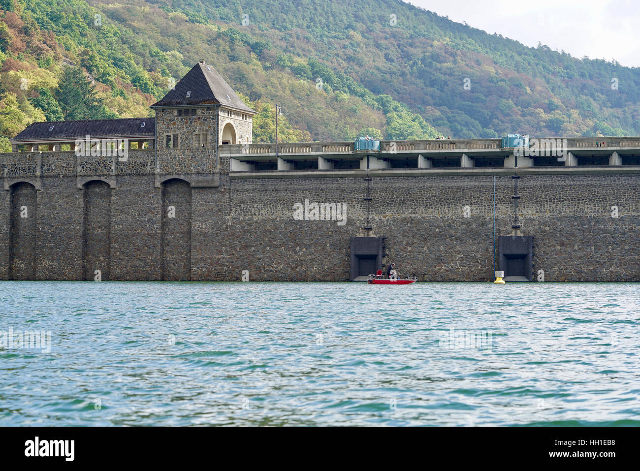 view from the Edersee to the dam, a fishing boat in front of the wall Stock Photo