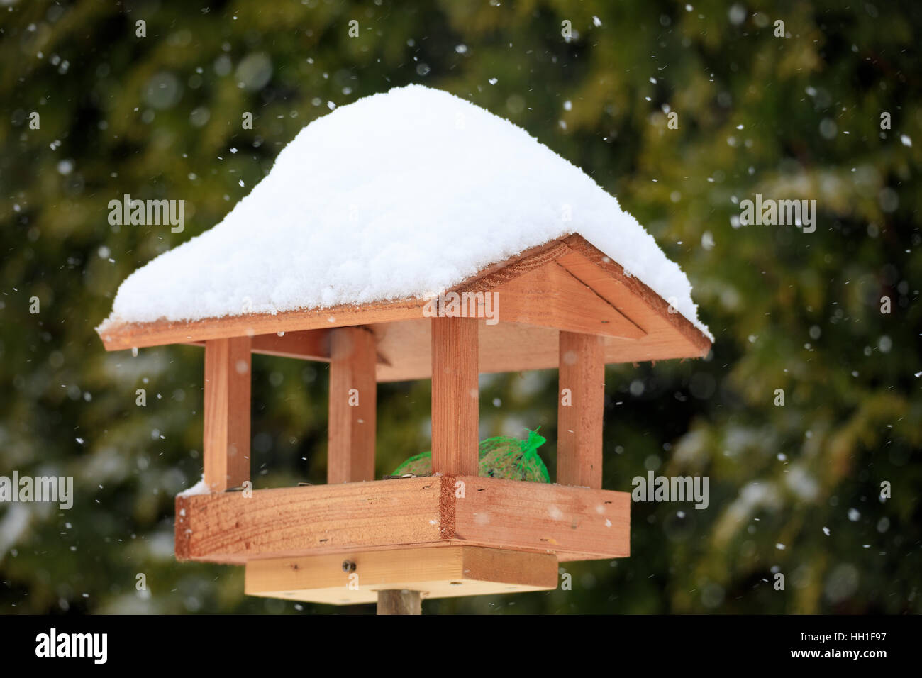 simple homemade wooden bird feeder, birdhouse installed on winter garden in snowy day Stock Photo