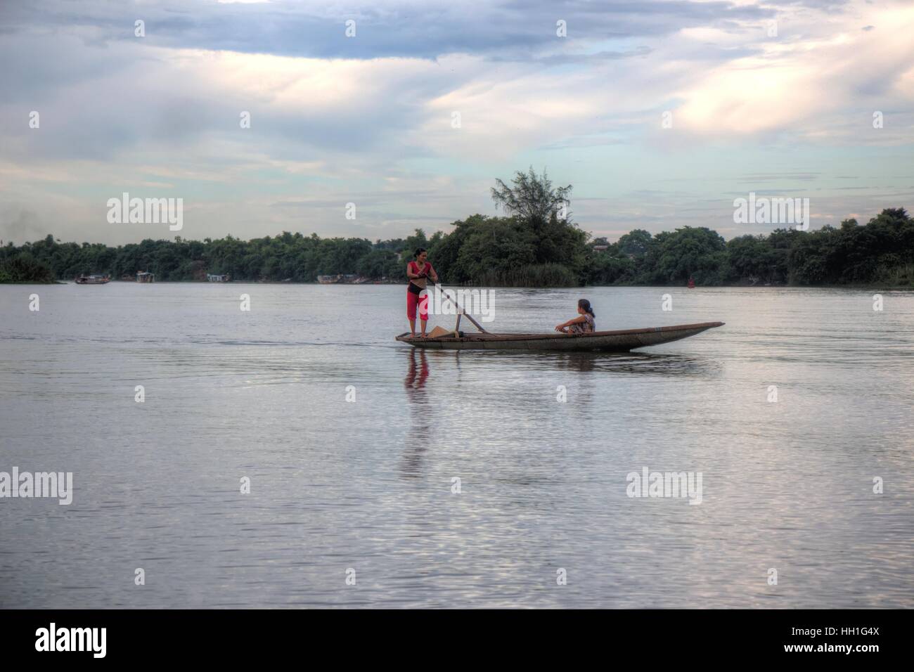 A woman rowing a boat with a passenger, down the Perfume River, Hue, Vietnam. Stock Photo