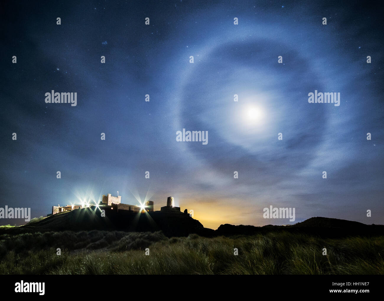 A 22° lunar halo over Bamburgh Castle on Northumberland coast in the UK Stock Photo