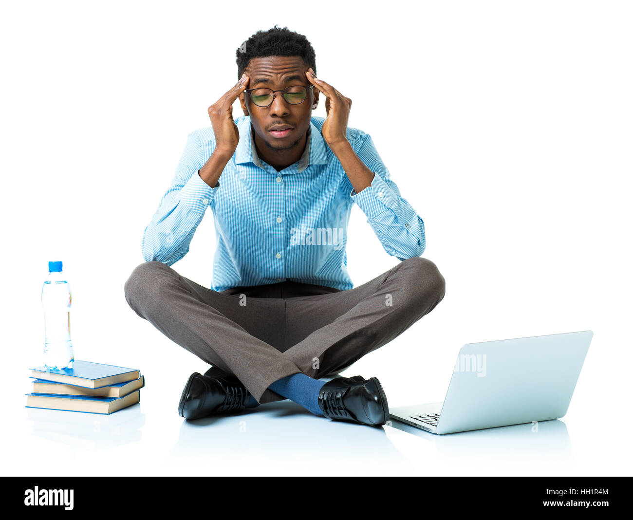 Happy african american college student in stress sitting with laptop, books and bottle of water on white background Stock Photo