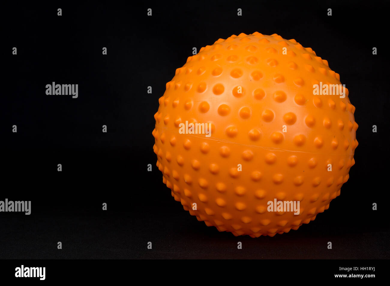 Orange spiky massage ball on black background Stock Photo