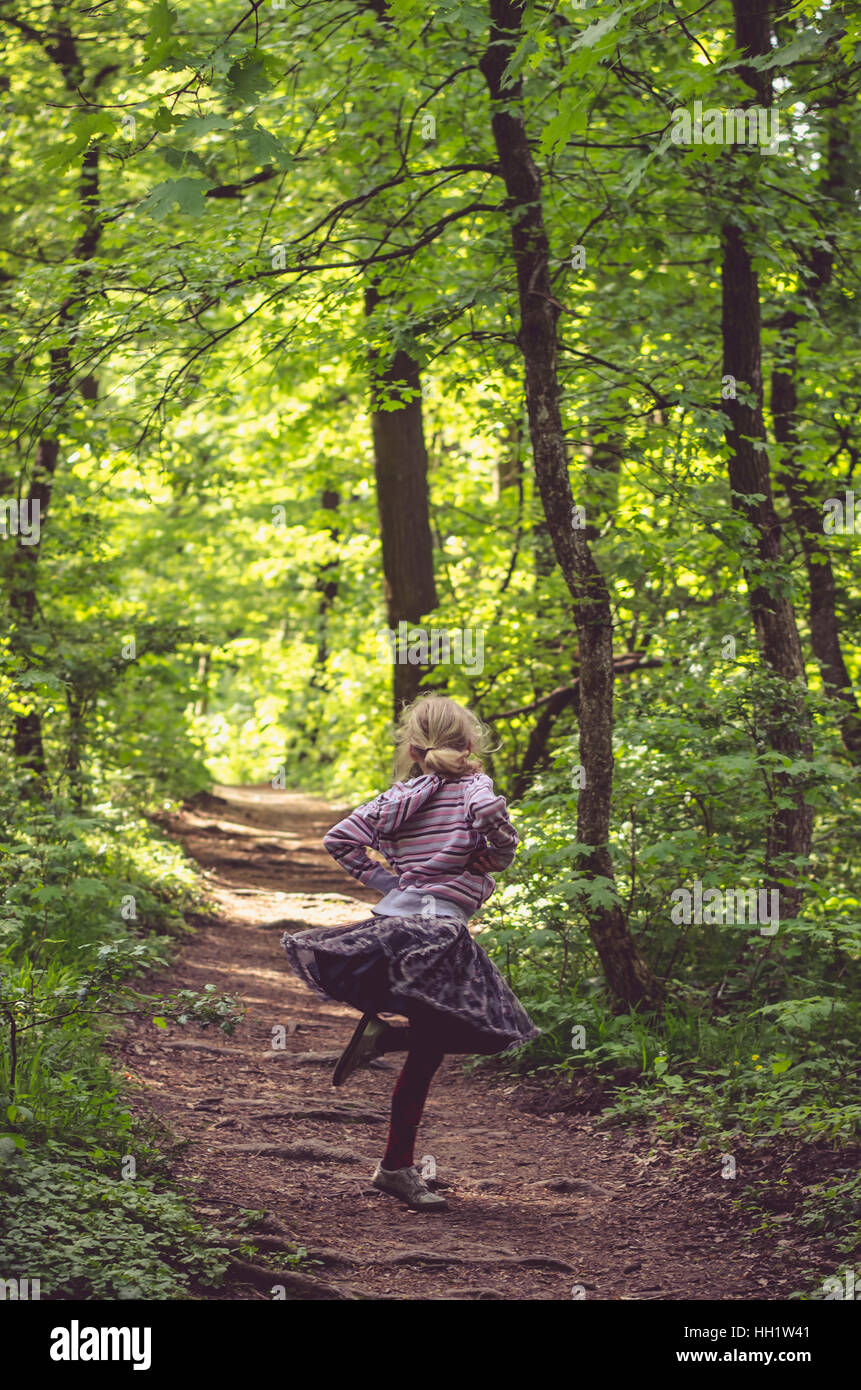 little girl dancing in path in dark green forest Stock Photo Alamy