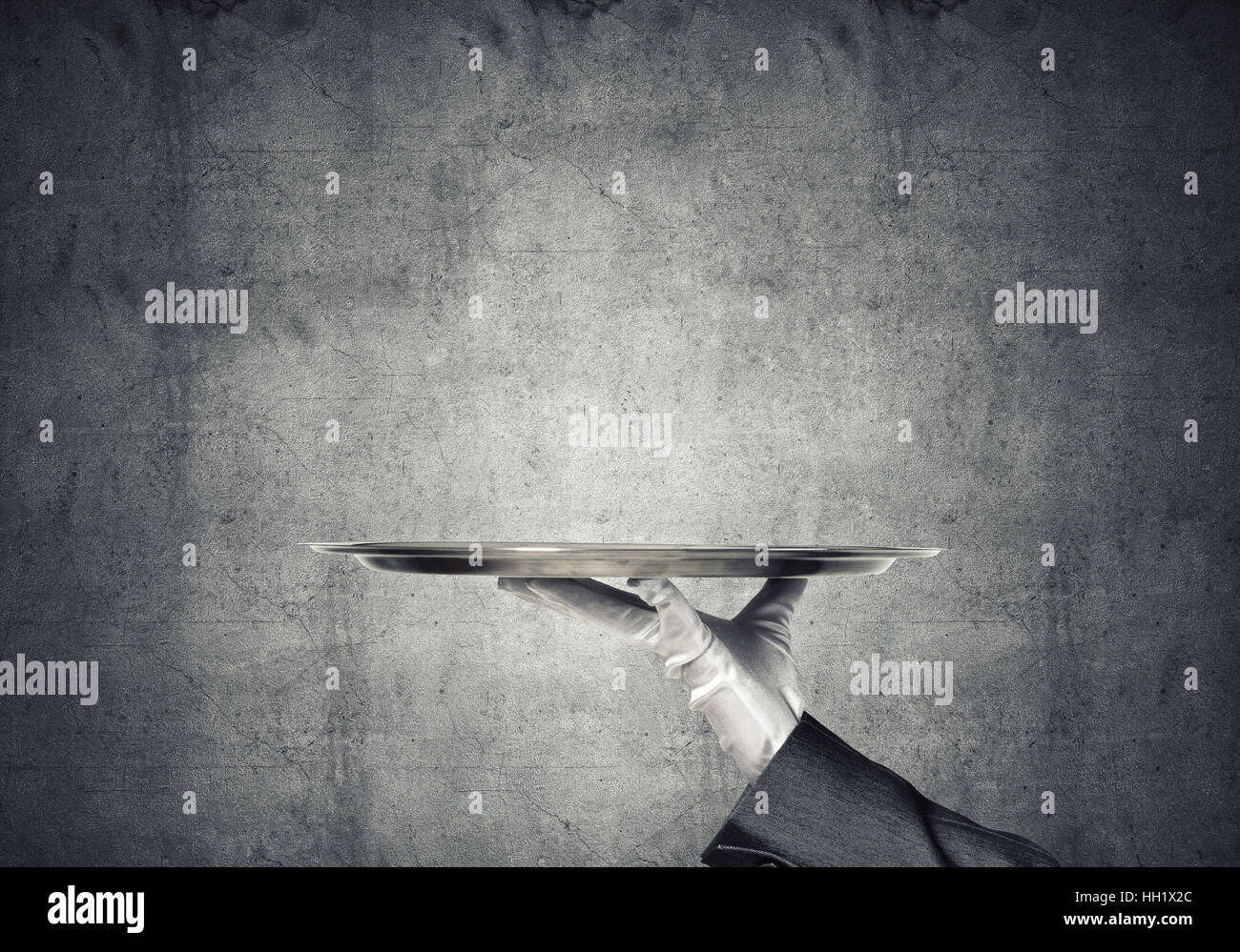 Hand of butler holding empty metal tray against concrete background ...