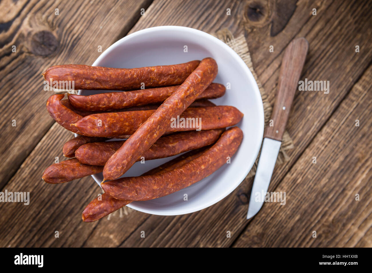 Chilli flavoured Sausages (German Mettwurst) on wooden background (selective focus) Stock Photo