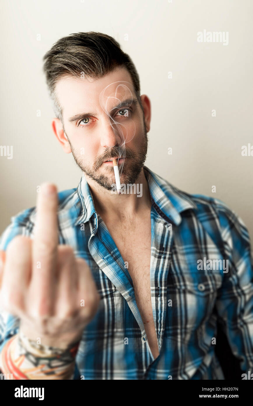 Smoking man flipping middle finger to viewer Stock Photo