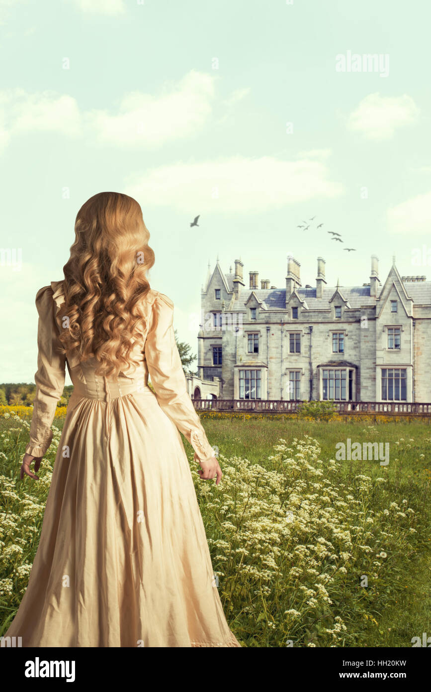 Woman in English countryside looking towards a country mansion Stock Photo
