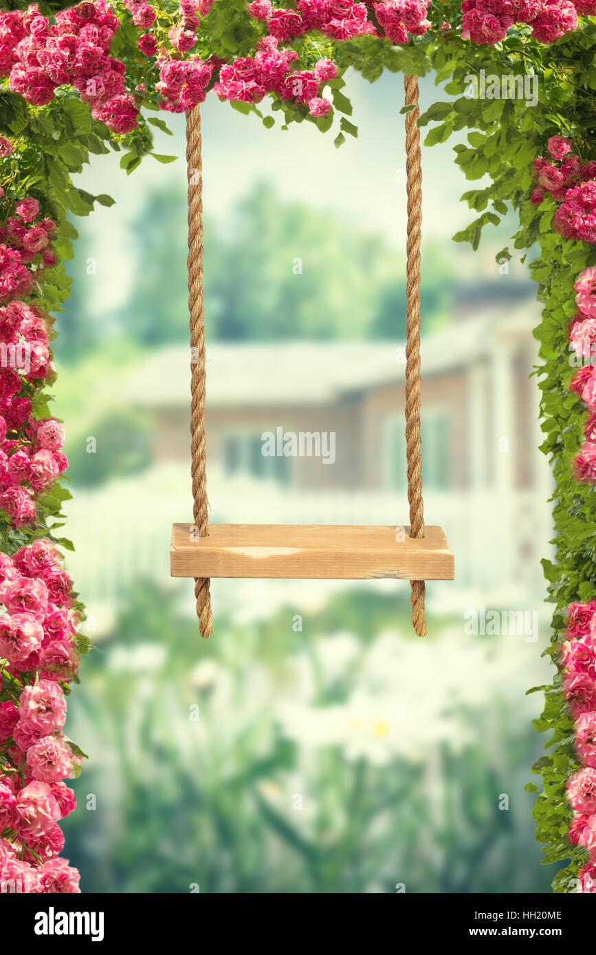 Garden rope swing amongst pink roses Stock Photo