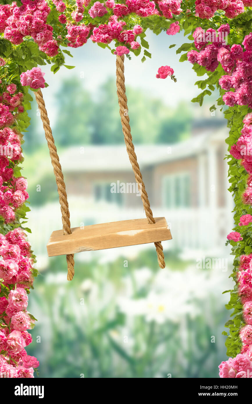 Garden rope swing in amongst English country roses Stock Photo