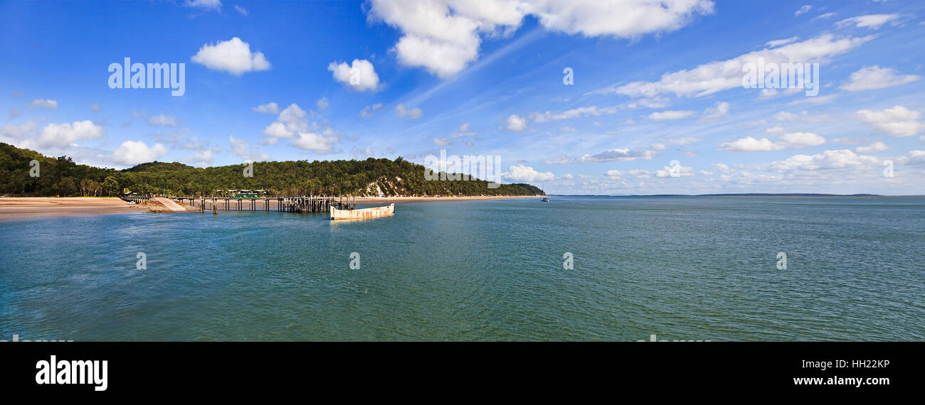 Kingfisher bay on west coast of Fraser Island. Passenger and cargo jetty with docked abandoned barge on a summer day in wide panoramic sight. Stock Photo