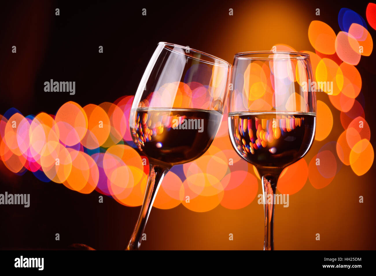 Two wine glasses clink at the party, background with blurred lights Stock Photo