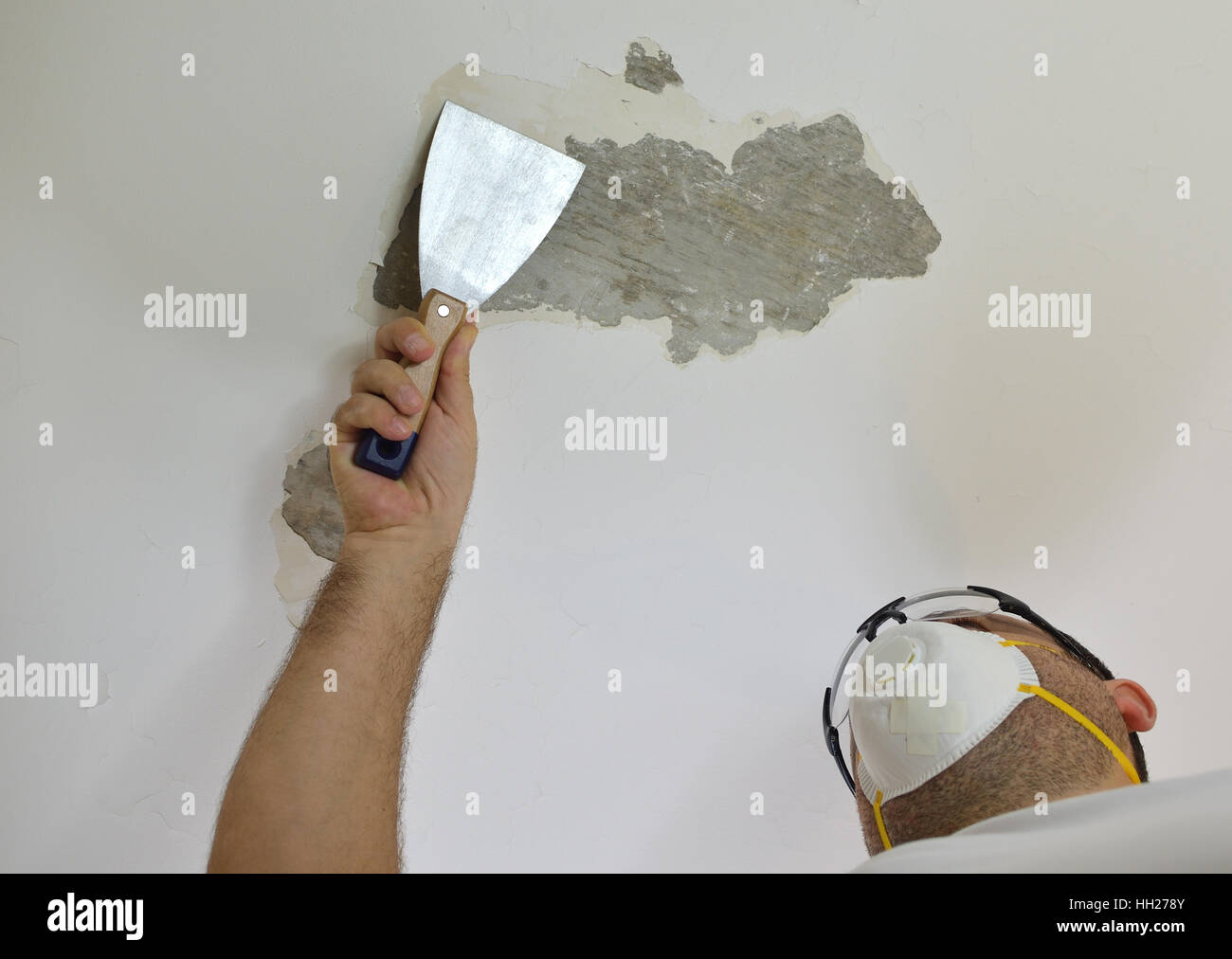 Man Scraping A Ceiling With A Plaster Spatula Preparing It