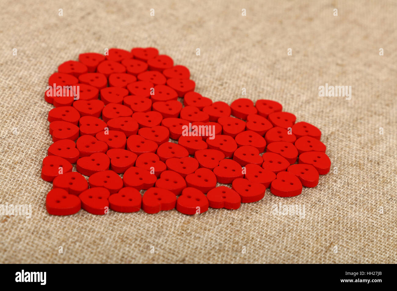 Red heart shaped handmade wooden sewing buttons on linen canvas, low ...