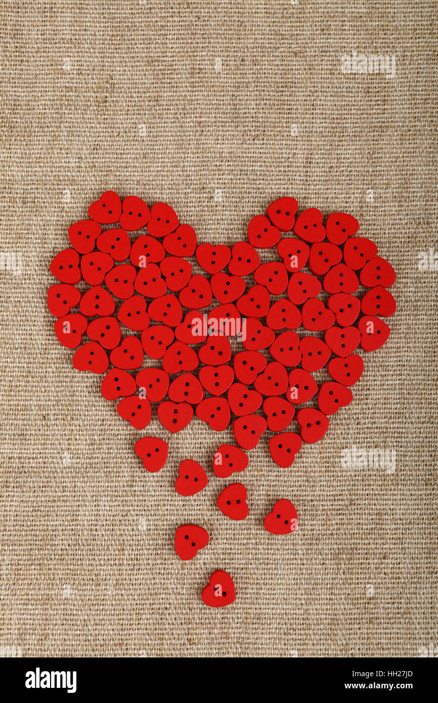 Red heart shaped handmade wooden sewing buttons form broken heart on linen canvas with copy space left, elevated top view Stock Photo