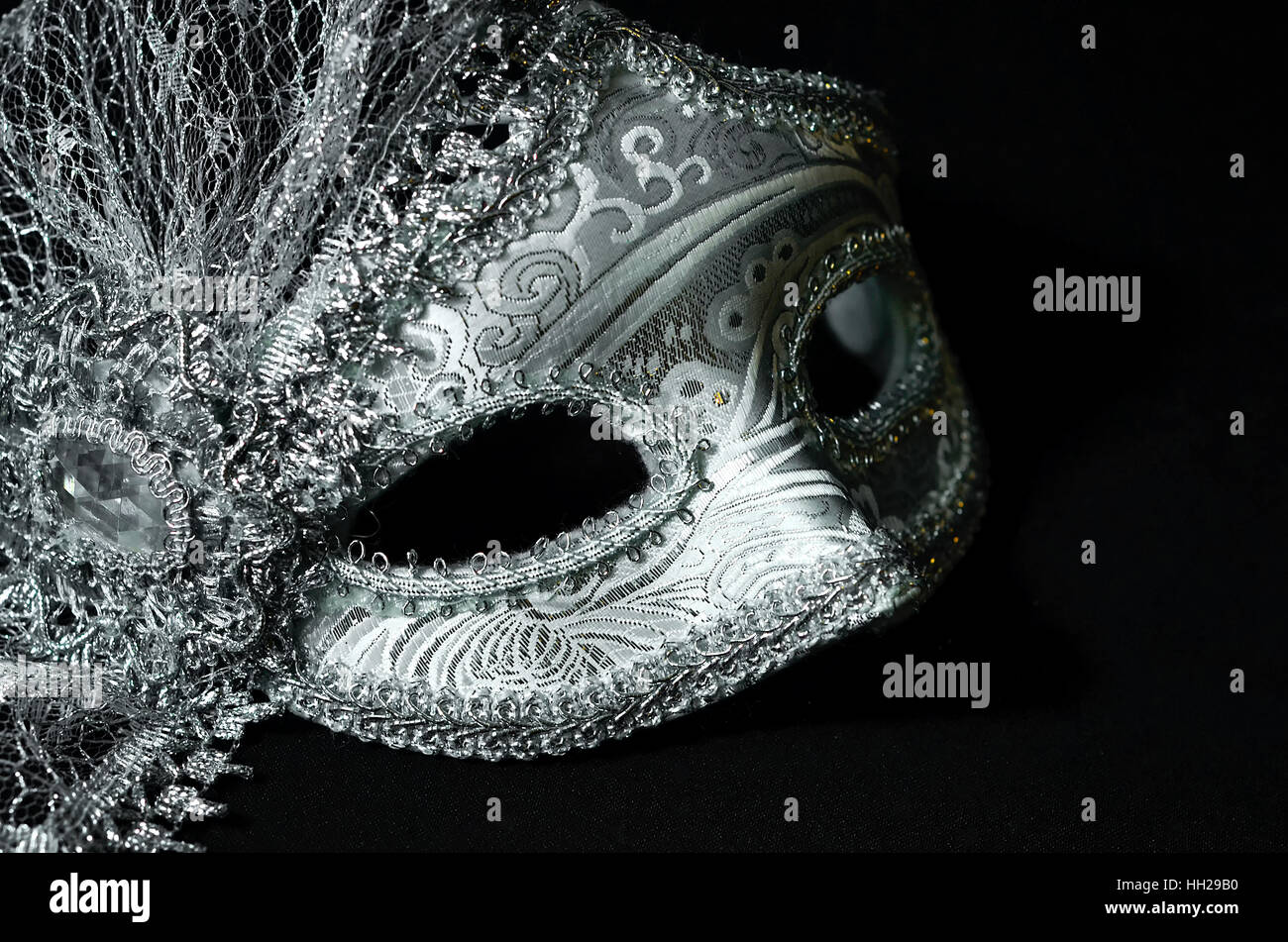 A close up of a silver masquerade mask on black background Stock Photo