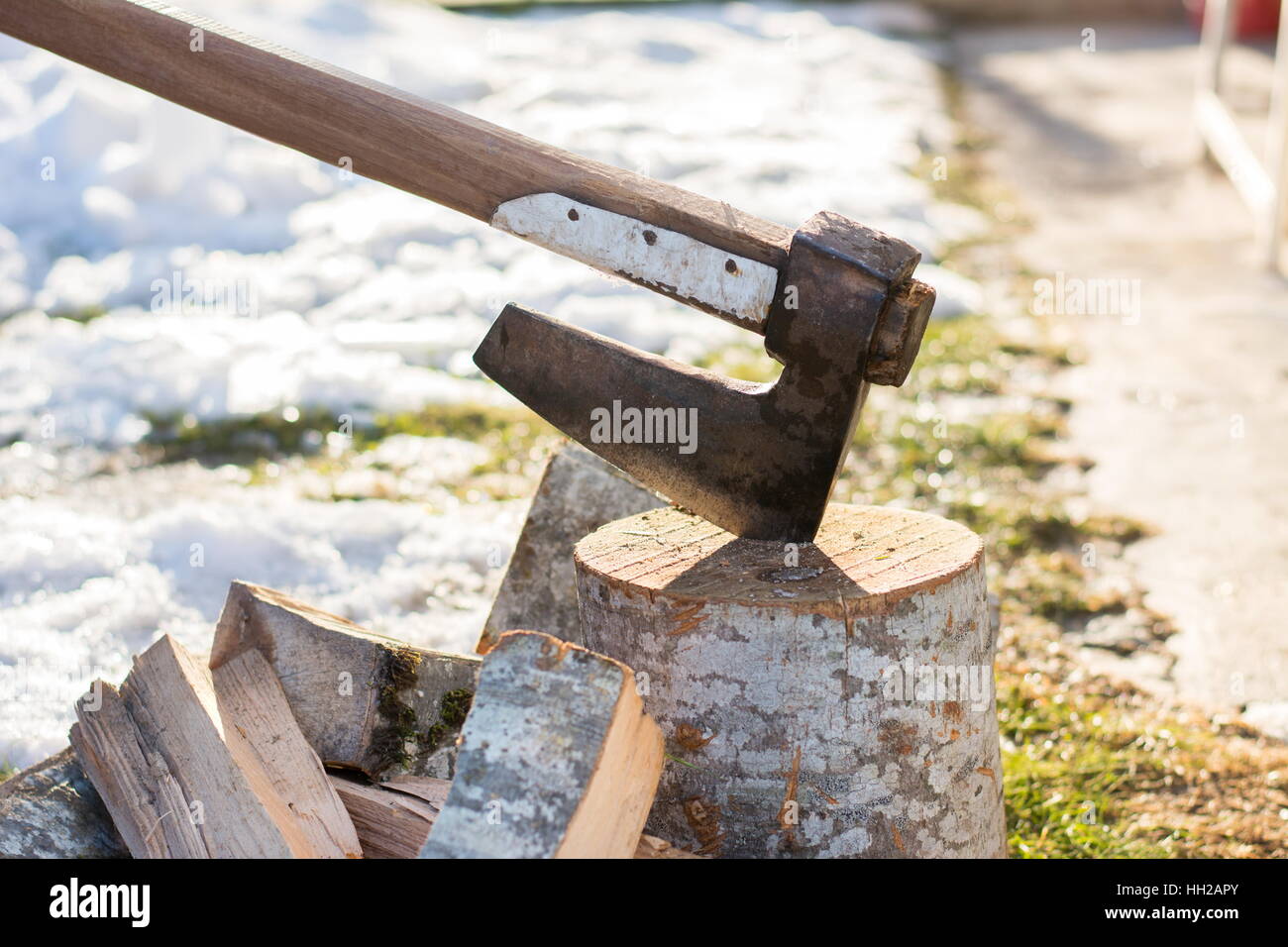 Axe stabbed in the firewood in the front yard Stock Photo