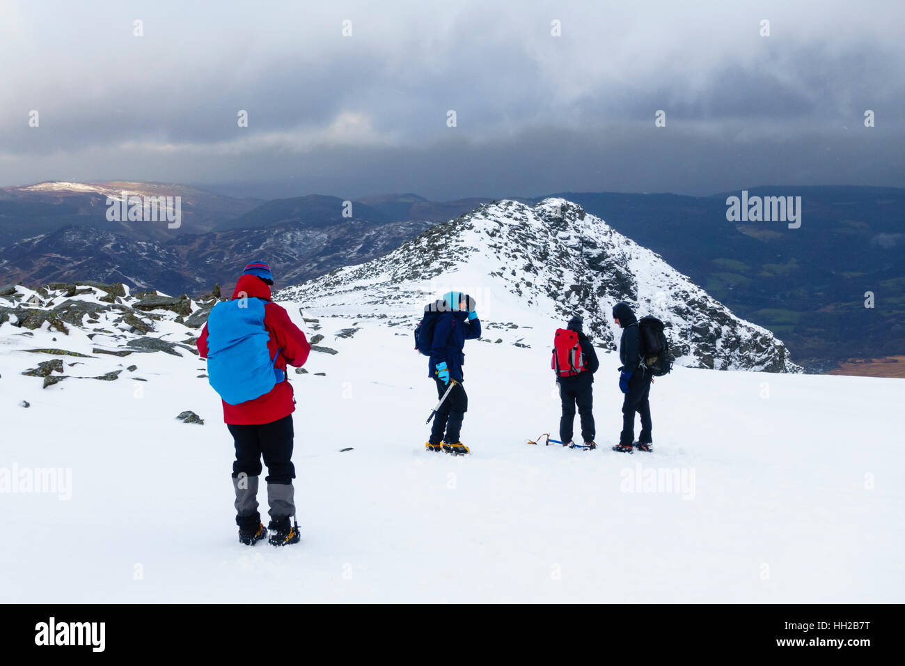 Hikers hiking in snow on Carnedd Moel Siabod mountain top summit ridge in Snowdonia in winter. Capel Curig, Conwy, Wales, UK, Britain Stock Photo