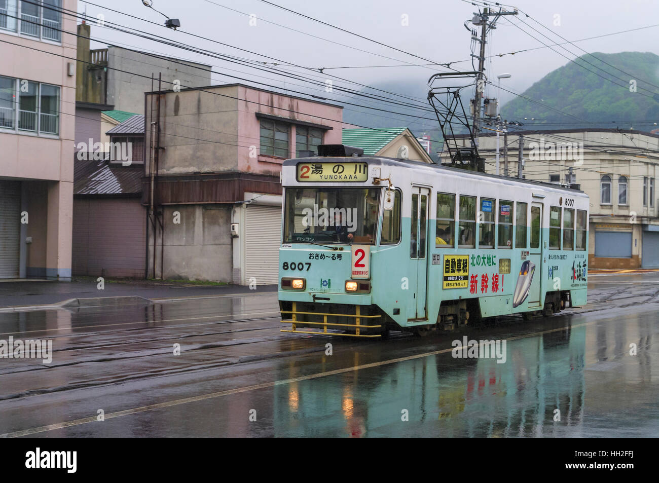 Streetcar of the Hakodate Tram running on Kaikyo Dori street on a rainy day. Hakodate, Hokkaido, Japan. Stock Photo