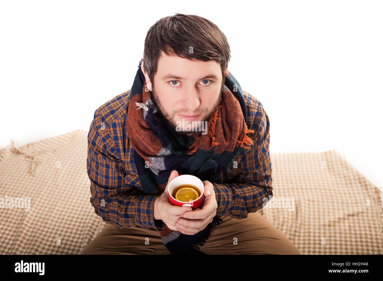 Portrait of a sick man with a fever wrapped in a blanket and holding a warm tea cup Stock Photo