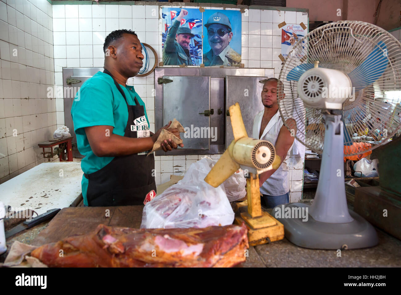 Men at work in a shop in havana with Fidel and raul Castro at the back on the walls Stock Photo