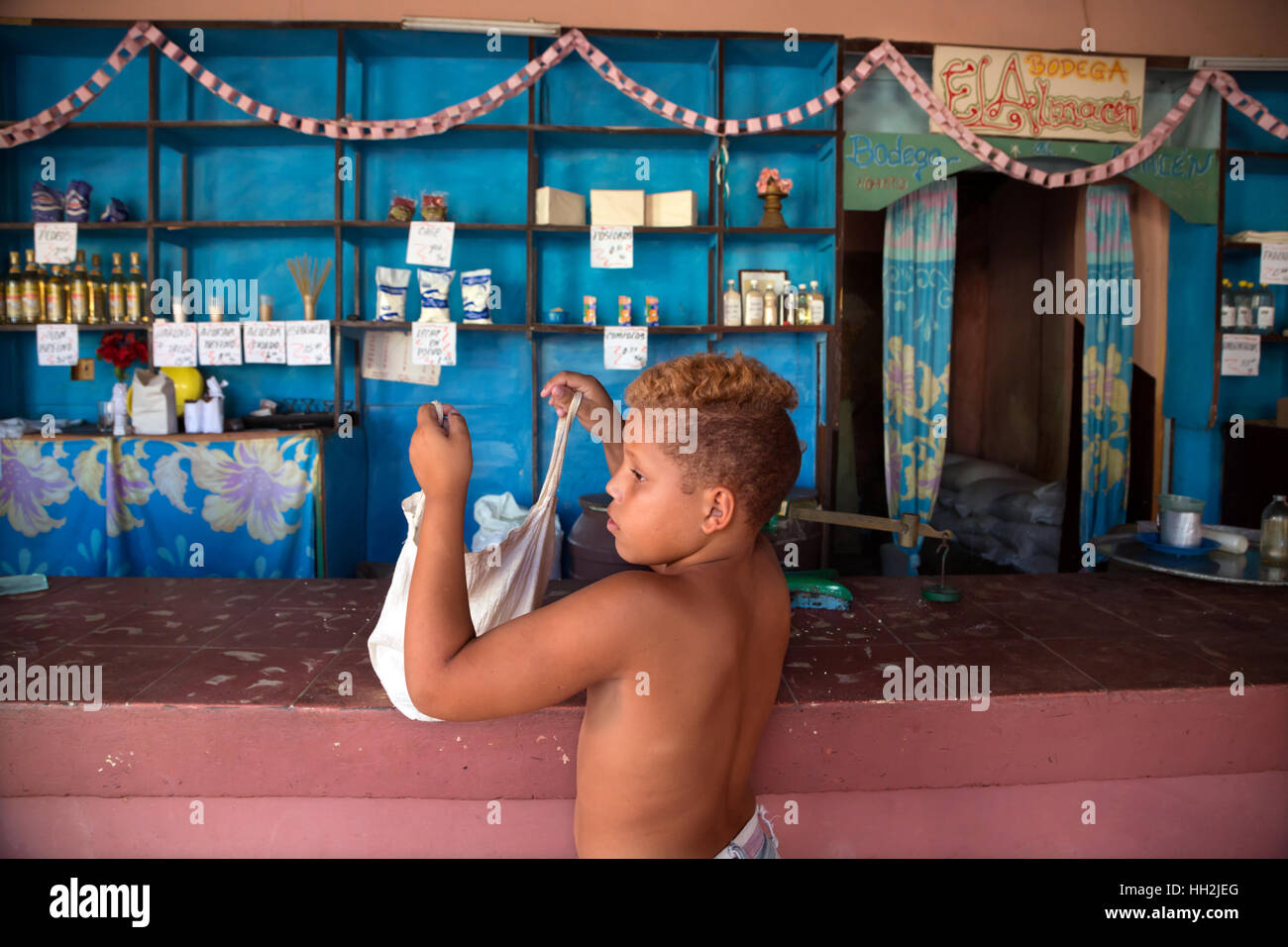 A boy packs his things after shopping in a typical and modestly provided Cuban «bodega» (shop), Trinidad, Cuba Stock Photo