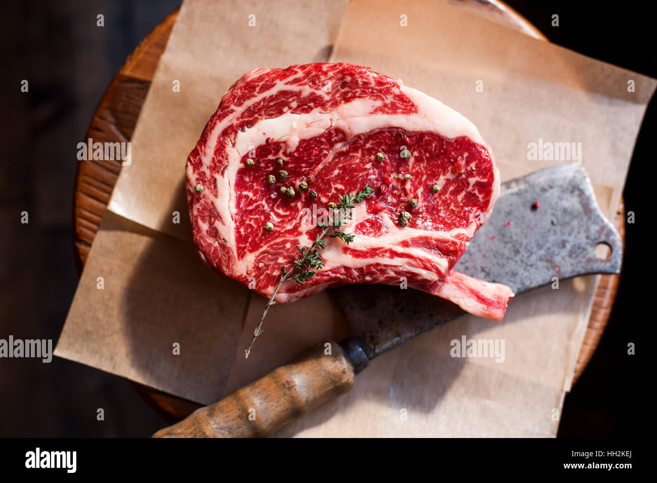 Bone In Rib Eye row Steak on pieces of salt on a wooden board. Stock image Stock Photo