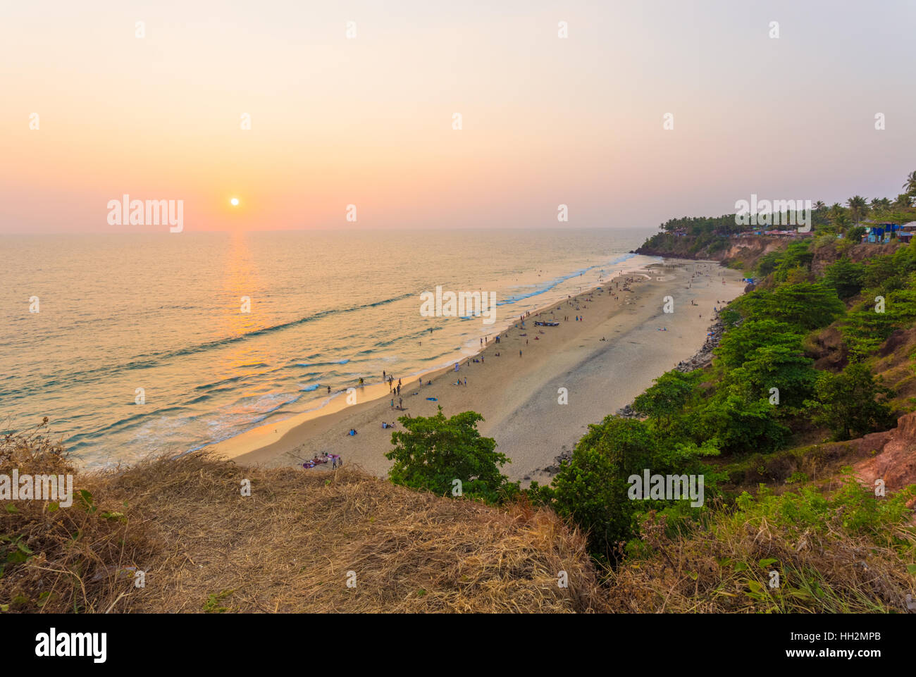 High angle view of beach and ocean during evening sunset as sun approaches horizon in cliffside tourist town Varkala, India Stock Photo