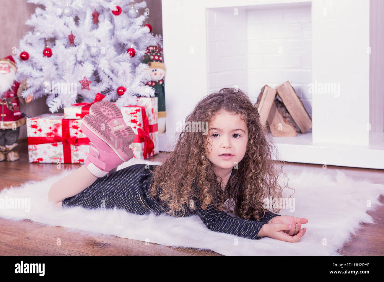 Portrait of pretty little girl near a fireplace in Christmas Stock Photo