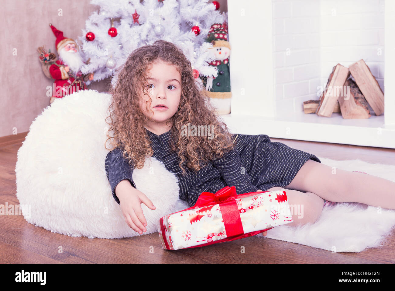 Portrait of pretty little girl near a fireplace in Christmas Stock Photo