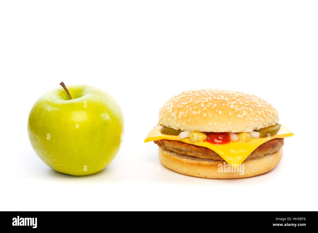 Choose: green apple or a cheeseburger. Against white background Stock Photo