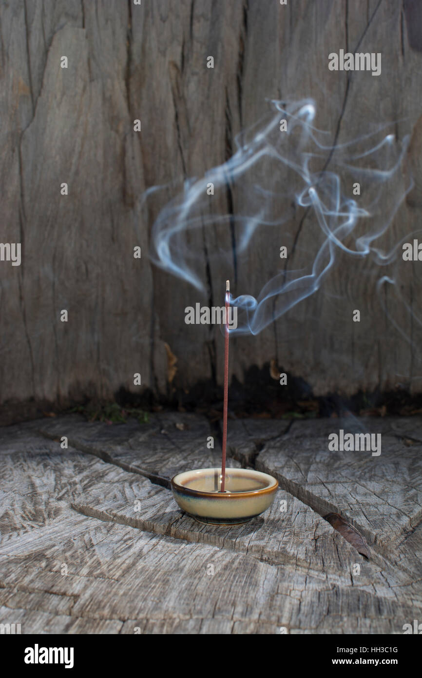 Incense burning with smoke during meditation behind wood promotes a