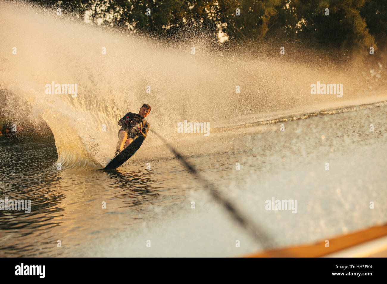 Man wakeboarding on a lake. Wakeboarder surfing across the lake. Stock Photo