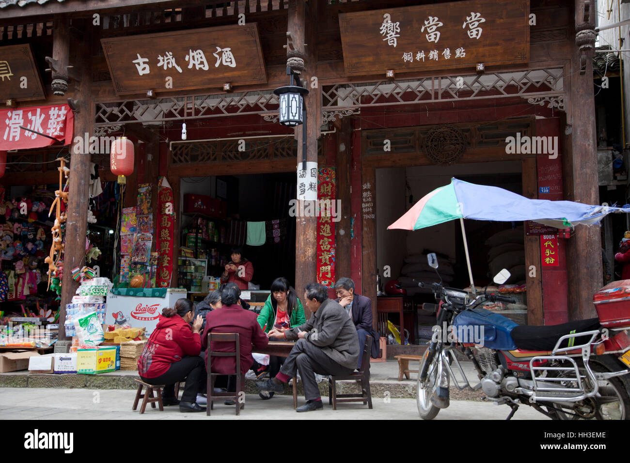Idle shopkeepers play cards outside their shops in Qingxi's reconstructed old town in west China. Stock Photo