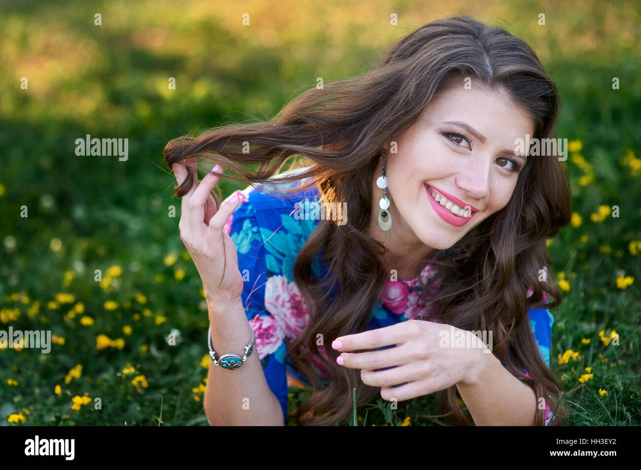 smiling young woman lying on the grass in the summer Park Stock Photo